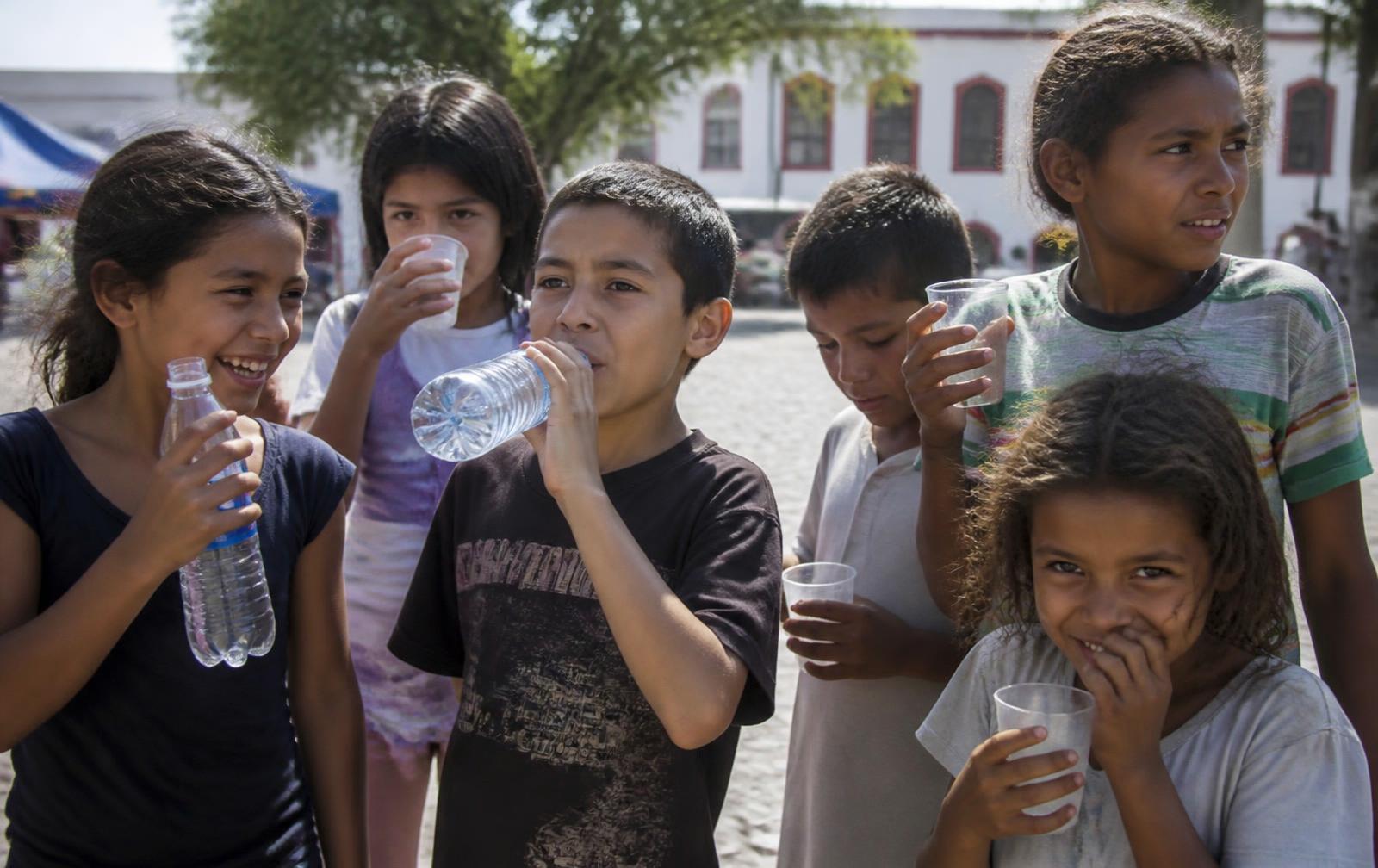 Children drinking bottled water distributed as part of a charity project